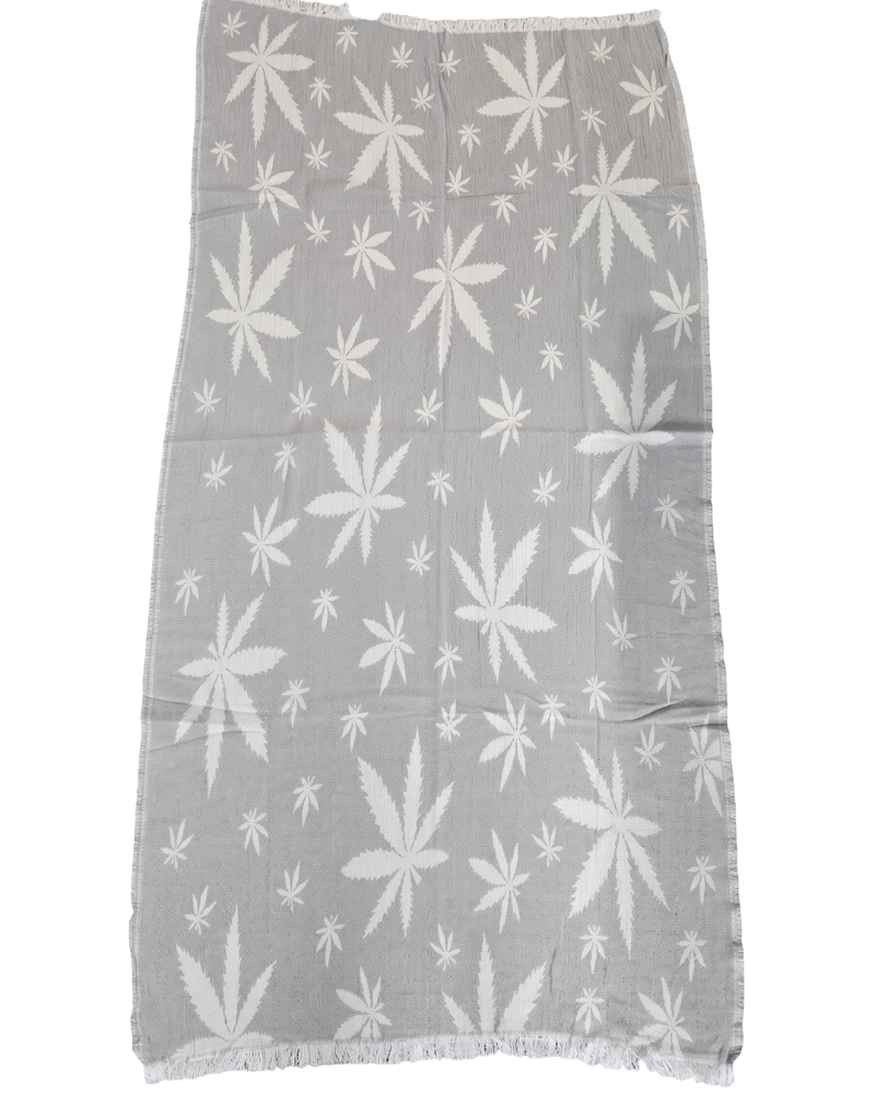plazhna-karpa-peshtemal-hemp-style-siva-variant-1 Елегантна сива плажна кърпа тип пещемал с бели конопени листа, разстлана върху дървен шезлонг край басейна.